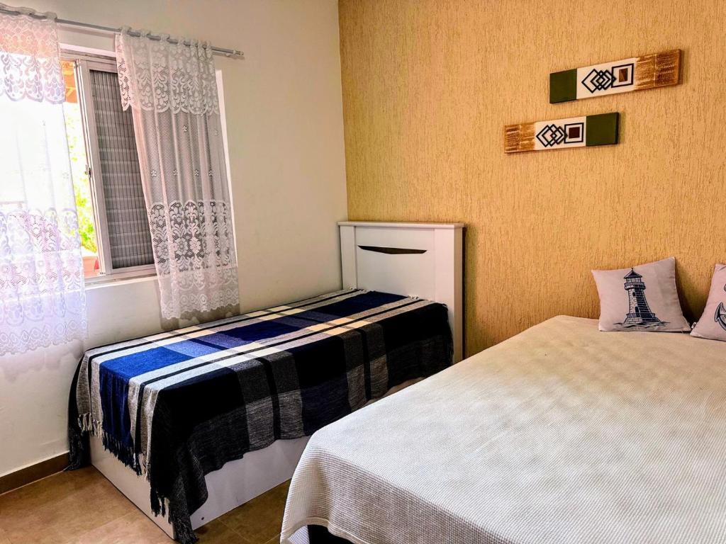 1 dormitorio con 2 camas y ventana en Praia Martin de Sá SP., en Caraguatatuba