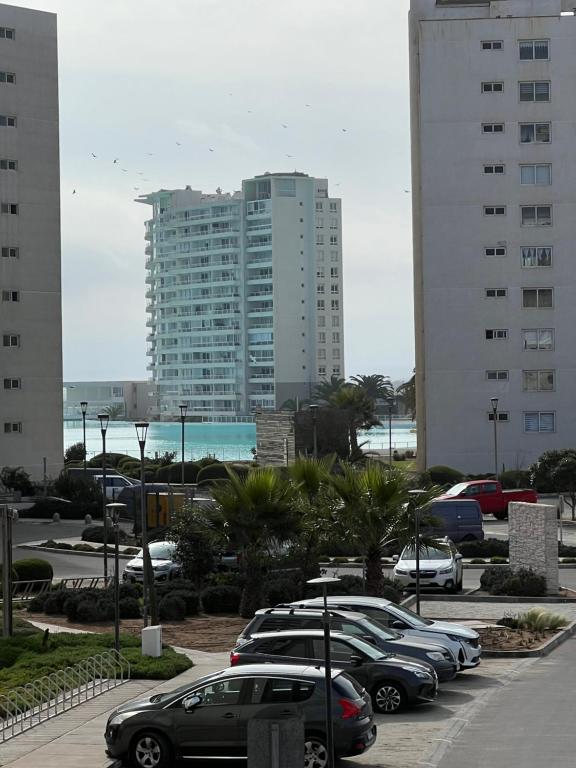 a parking lot with cars parked in front of a tall building at Laguna del Mar, Playa Arrecife in La Serena