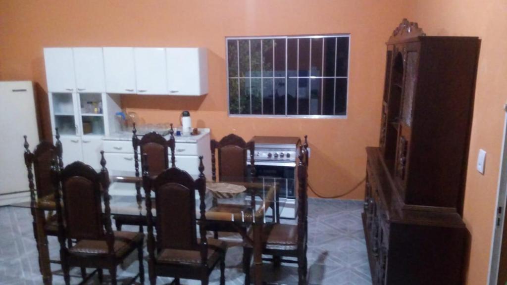 Un comedor con mesa y sillas y una cocina. en Rancho do Carlinhos, en Ipoema