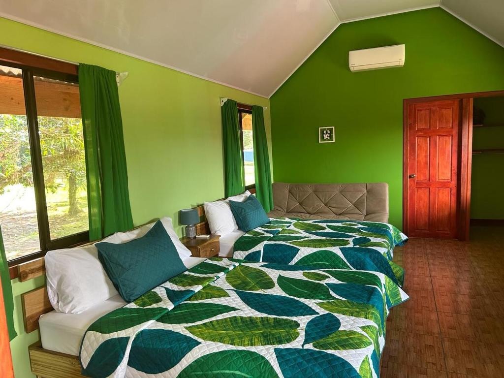 ein grünes Schlafzimmer mit einem Bett und einem Sofa in der Unterkunft Cabinas Tortuguero Sports Fishing in Tortuguero