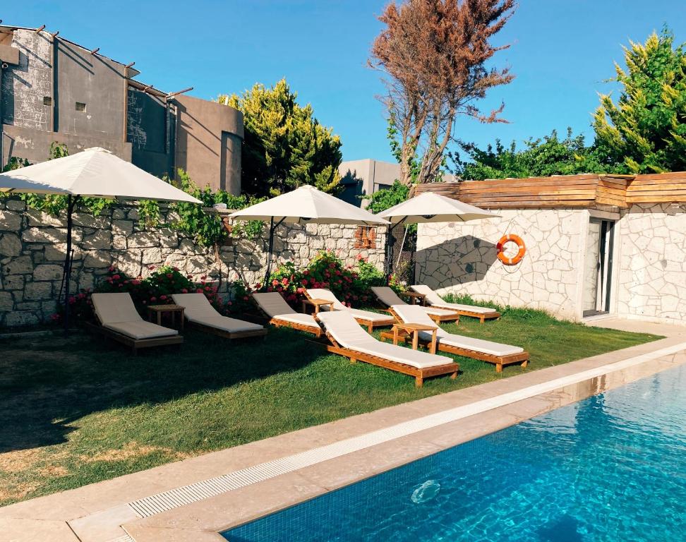 una piscina con tumbonas y sombrillas junto a una piscina en Limon Hotel, en Cesme