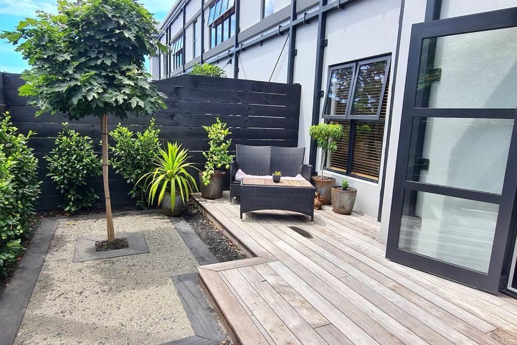 a patio with a chair and a table and a building at Apartment 1 - Haddin Court - Executive One Bedroom in Blenheim