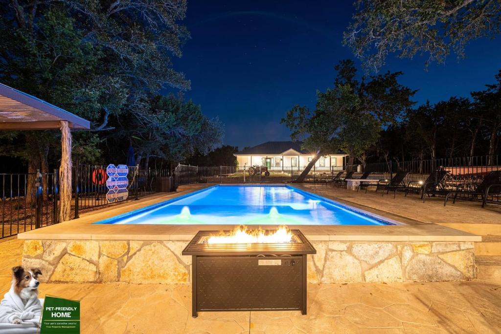 a dog sitting next to a swimming pool at night at Terracotta Bliss Wimberley Retreat For 28 Guests in Wimberley