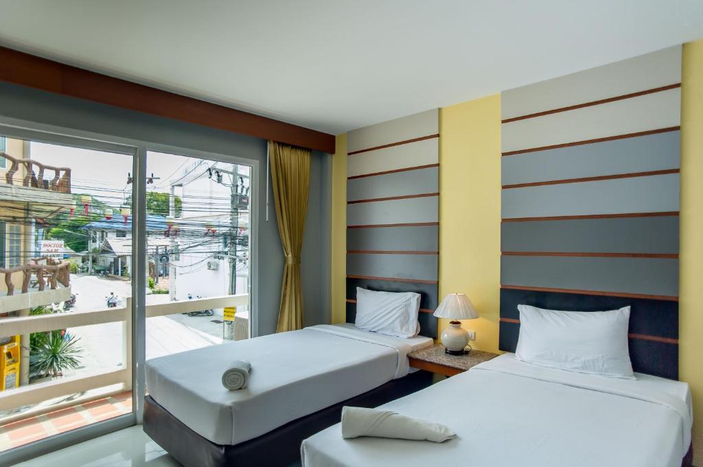 two beds in a room with a window at Phangan Pearl Villa in Haad Rin