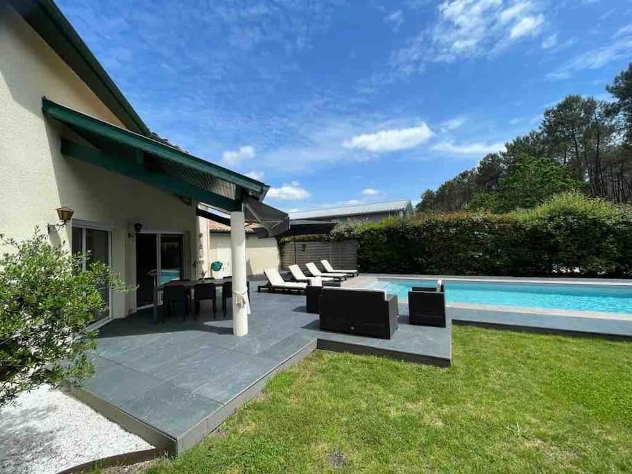 un patio avec une table et des chaises à côté d'une piscine dans l'établissement Villa familiale 8 personnes, piscine chauffée à 10 kms de la mer, à Saubion