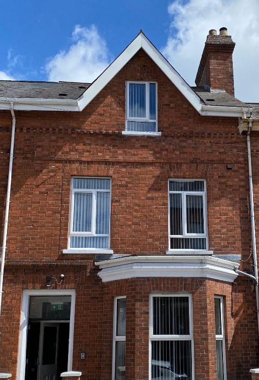 a red brick house with white windows on it at Roskeen Townhouse in Belfast