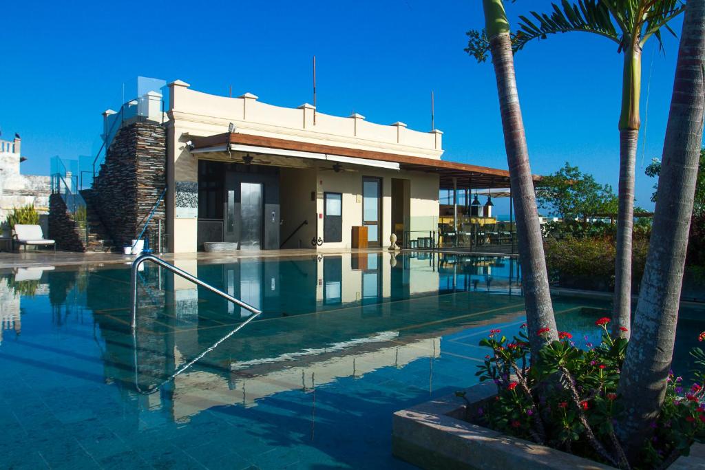una piscina con un edificio e palme di Bastión Luxury Hotel a Cartagena de Indias