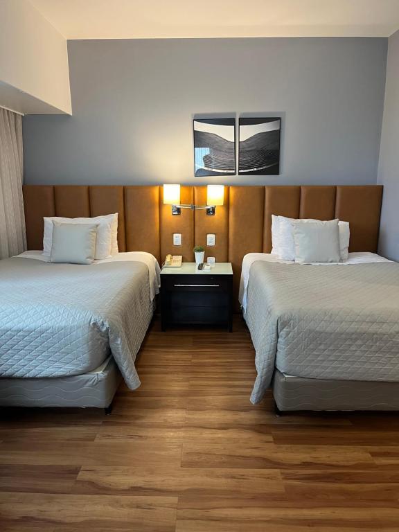 um quarto de hotel com duas camas e uma mesa em Suite 505 Wynd Berrini WTC - SP em São Paulo