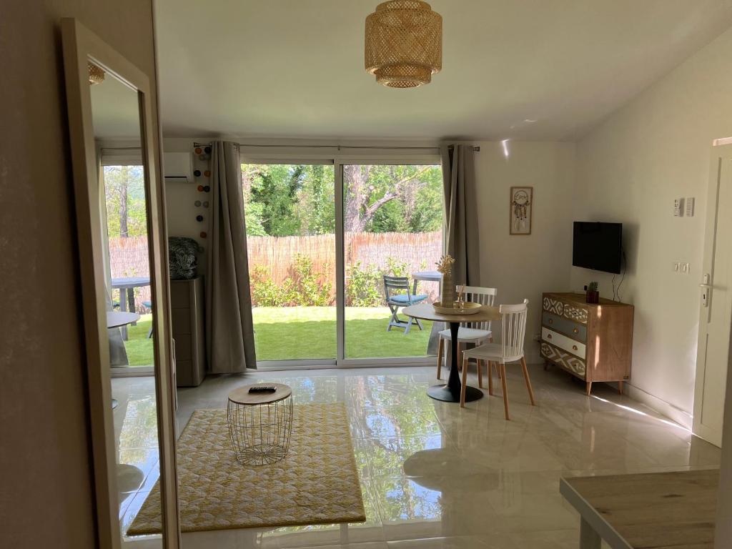 d'un salon avec une table, des chaises et une porte coulissante en verre. dans l'établissement Bienvenue chez vous, à Saint-Cézaire-sur-Siagne