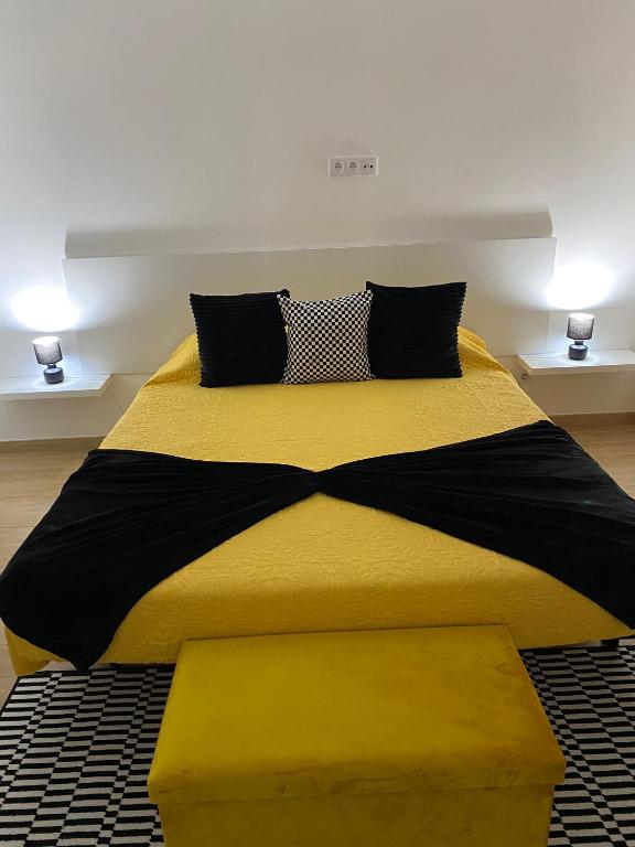 uma cama com um edredom amarelo e preto em O Infinito em Calhetas