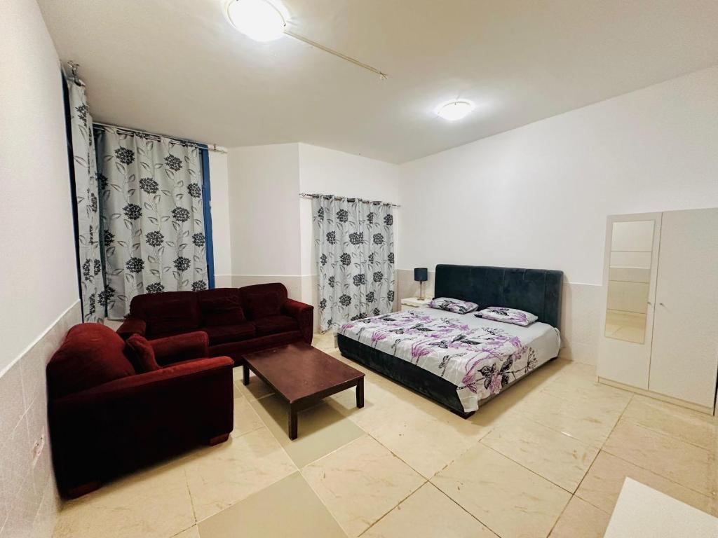 a bedroom with a bed and a couch and a chair at Lux Living Room in Ajman 