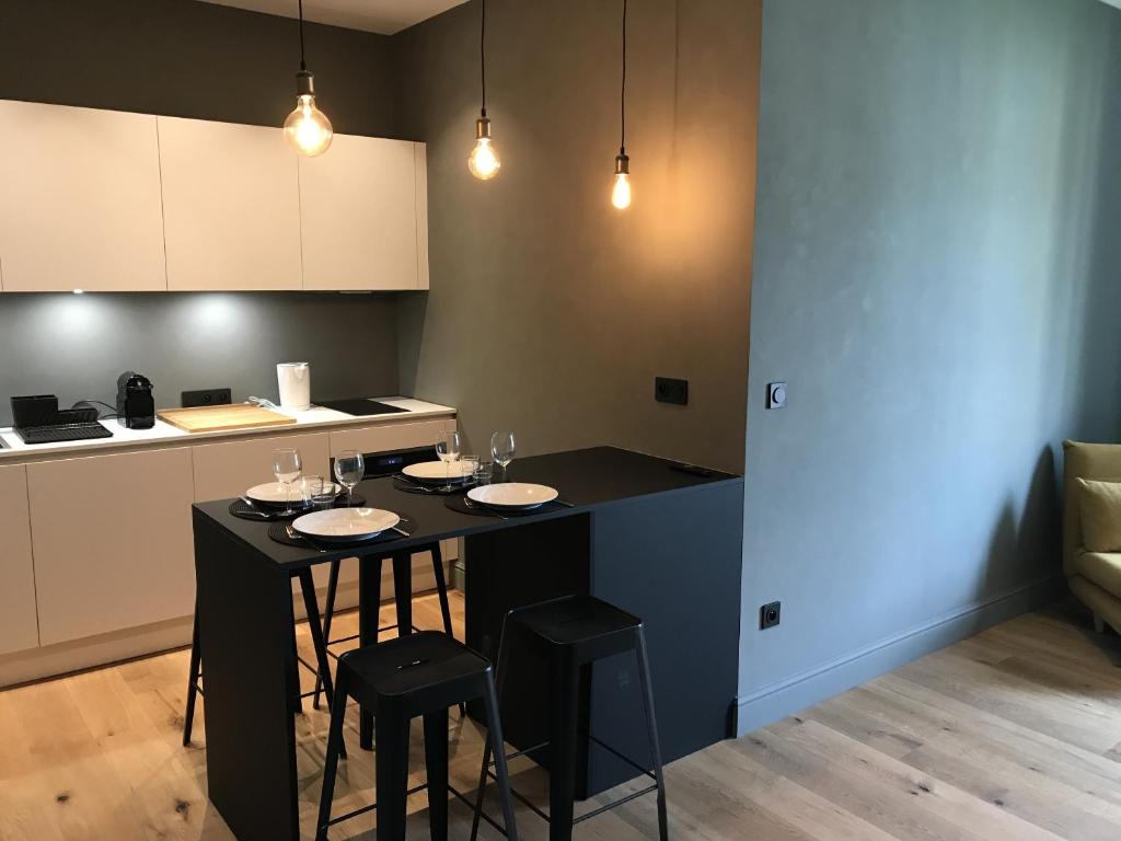 une cuisine avec un îlot noir et deux tabourets dans l'établissement Les Terrasses de Padoue, à Corte