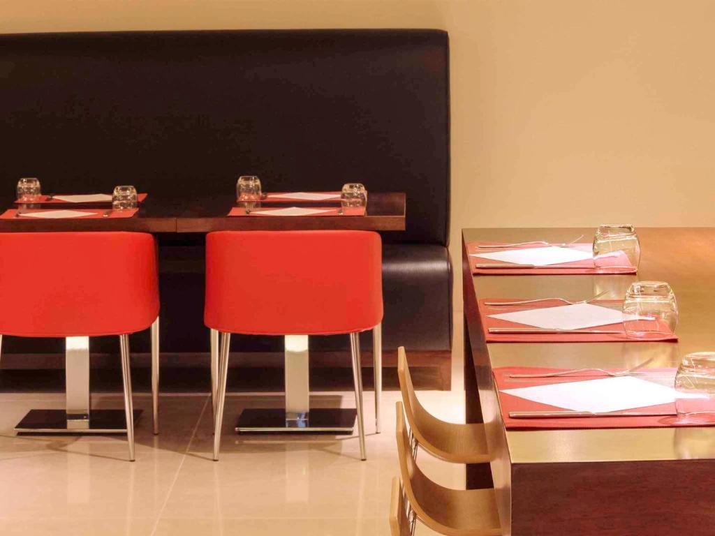 un comedor con 2 mesas y sillas rojas en Ibis Riyadh Olaya Street, en Riad