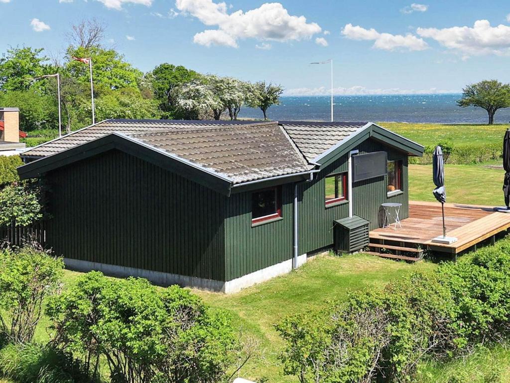 uma casa verde com um deque junto à água em Holiday home Præstø II em Praesto