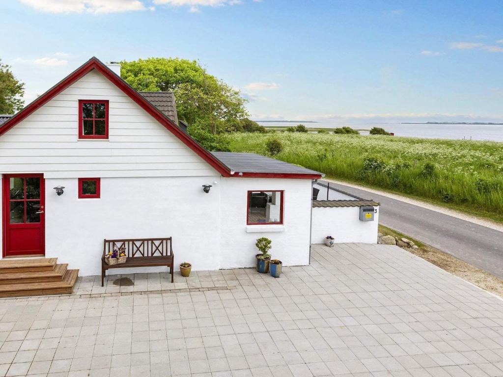 ein weißes Haus mit einer roten Tür auf einer Terrasse in der Unterkunft 6 person holiday home in Thisted in Arup