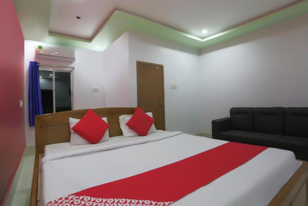 a bedroom with a bed with red and white pillows at OYO Flagship 67063 Roy Villa Resort in Baharampur