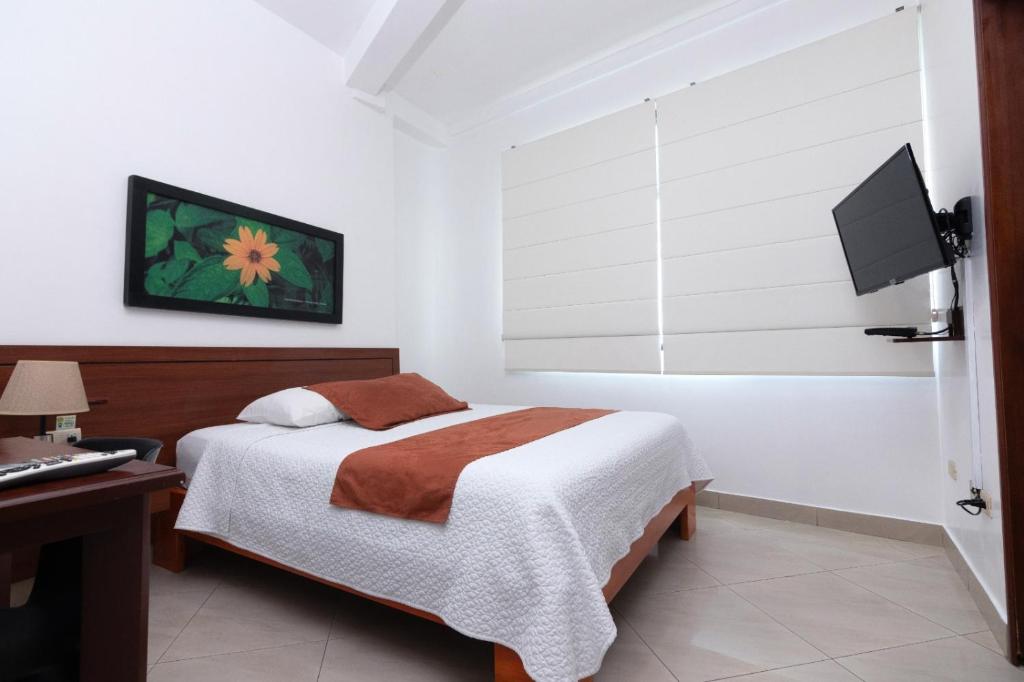 Dormitorio con cama, escritorio y TV en Hotel Castell, en Guayaquil