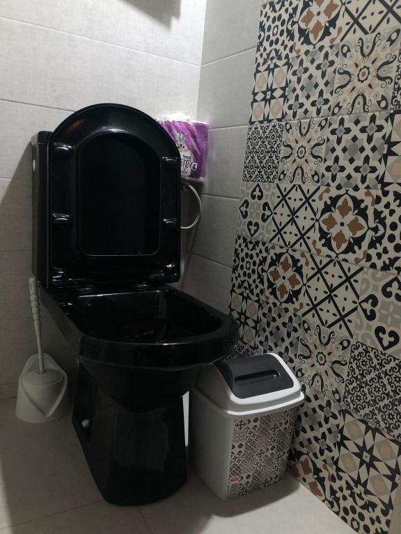 a bathroom with a black toilet and a trash can at apartment vue Mer in Agadir
