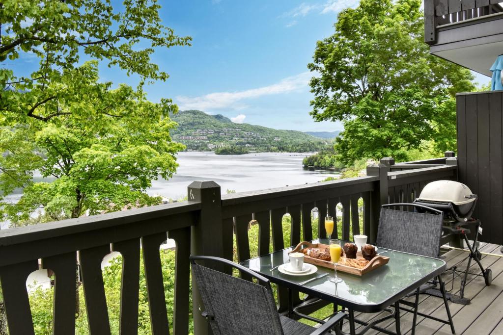 a table on a balcony with a view of a river at Stunning Condo - View on Lake Tremblant & Mountain in Mont-Tremblant