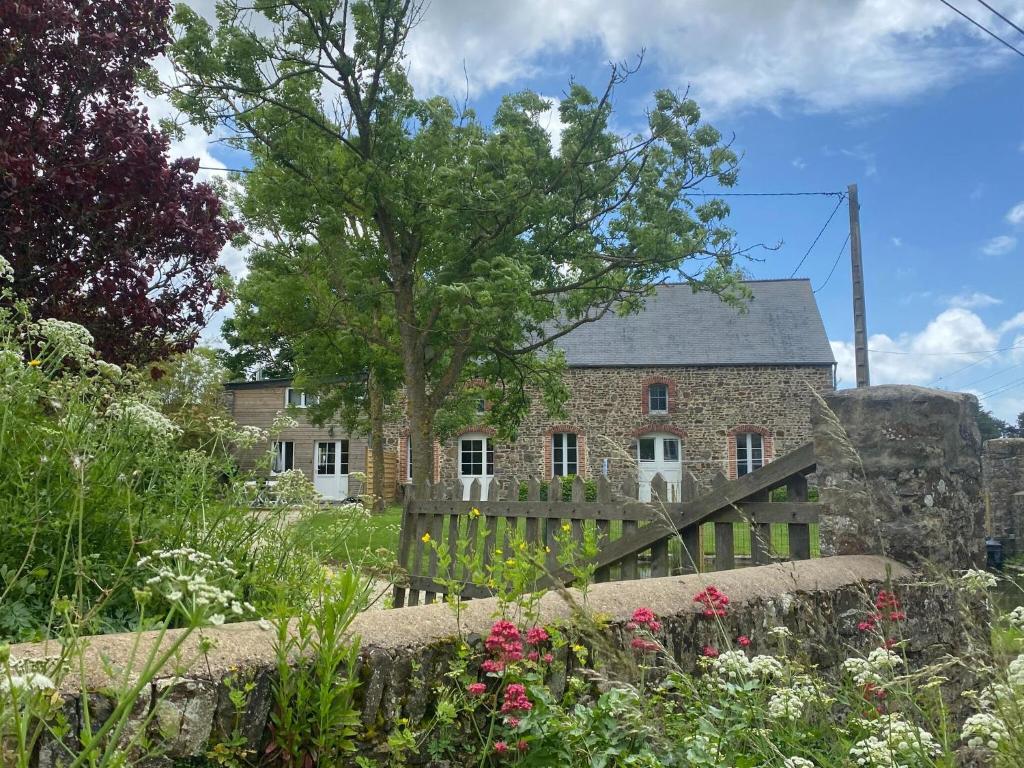 une vieille maison en pierre avec un arbre dans la cour dans l'établissement Terraced House in France near White Sand Beach, à Denneville