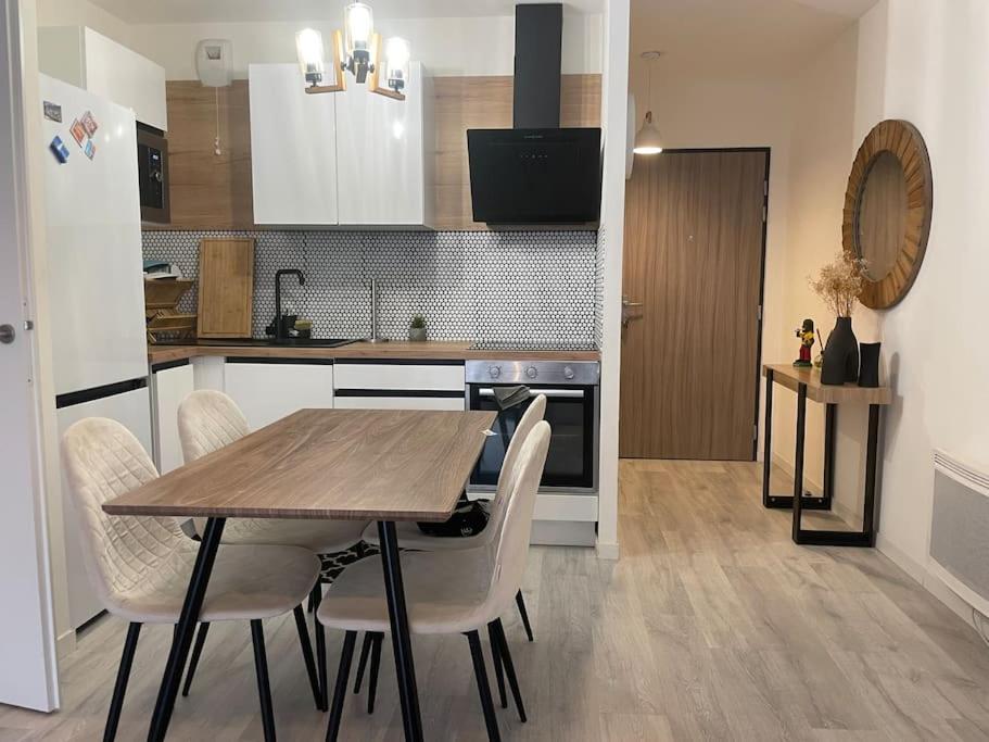 - une cuisine avec une table et des chaises en bois dans la chambre dans l'établissement Appartement 24h du Mans, au Mans