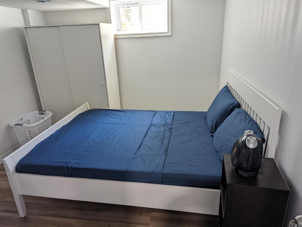 een slaapkamer met een bed met blauwe lakens en een raam bij House of Pleasantness in Hamilton