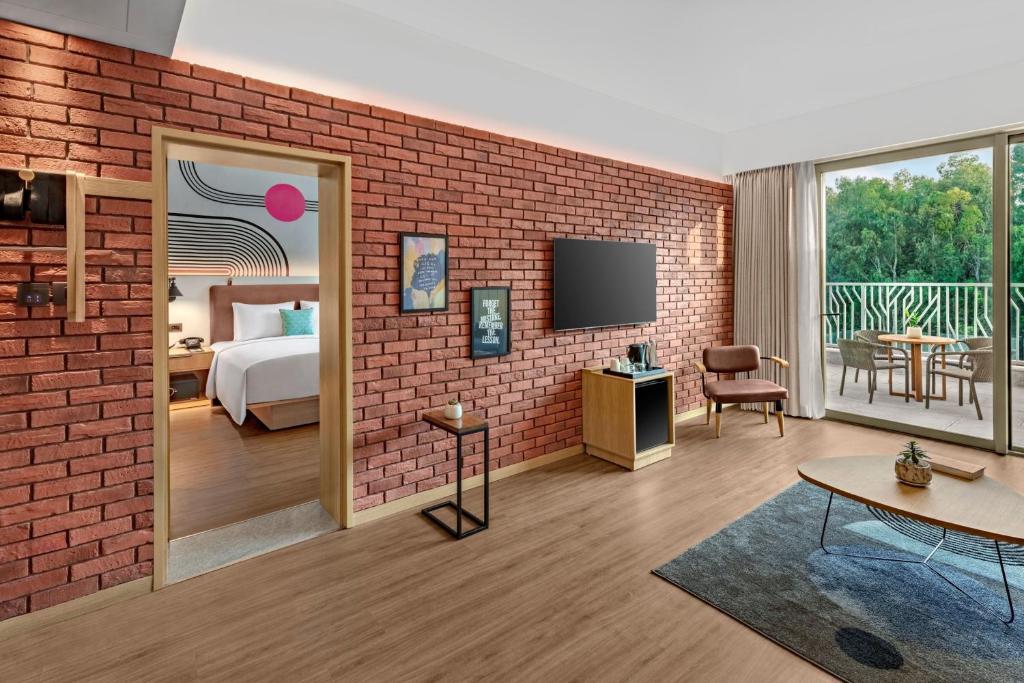 um quarto de hotel com uma parede de tijolos e um quarto em Moxy Bengaluru Airport Prestige Tech Cloud em Devanhalli