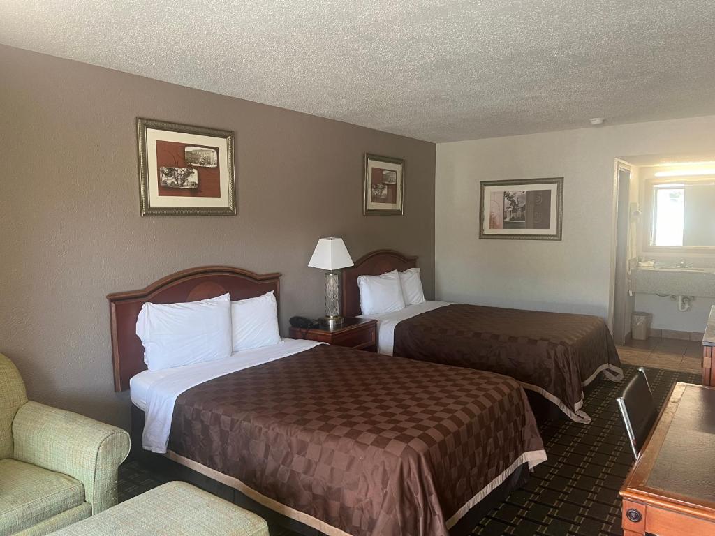 una habitación de hotel con 2 camas y una silla en American Inn Columbia en Columbia
