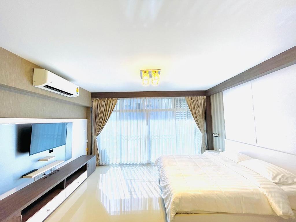 a bedroom with a large bed and a television at The Wellbeing House in Hat Yai