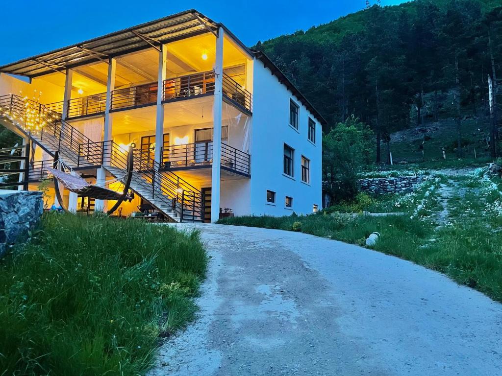 a building on a dirt road next to a mountain at Guesthouse SHAMPRIANI in Mestia
