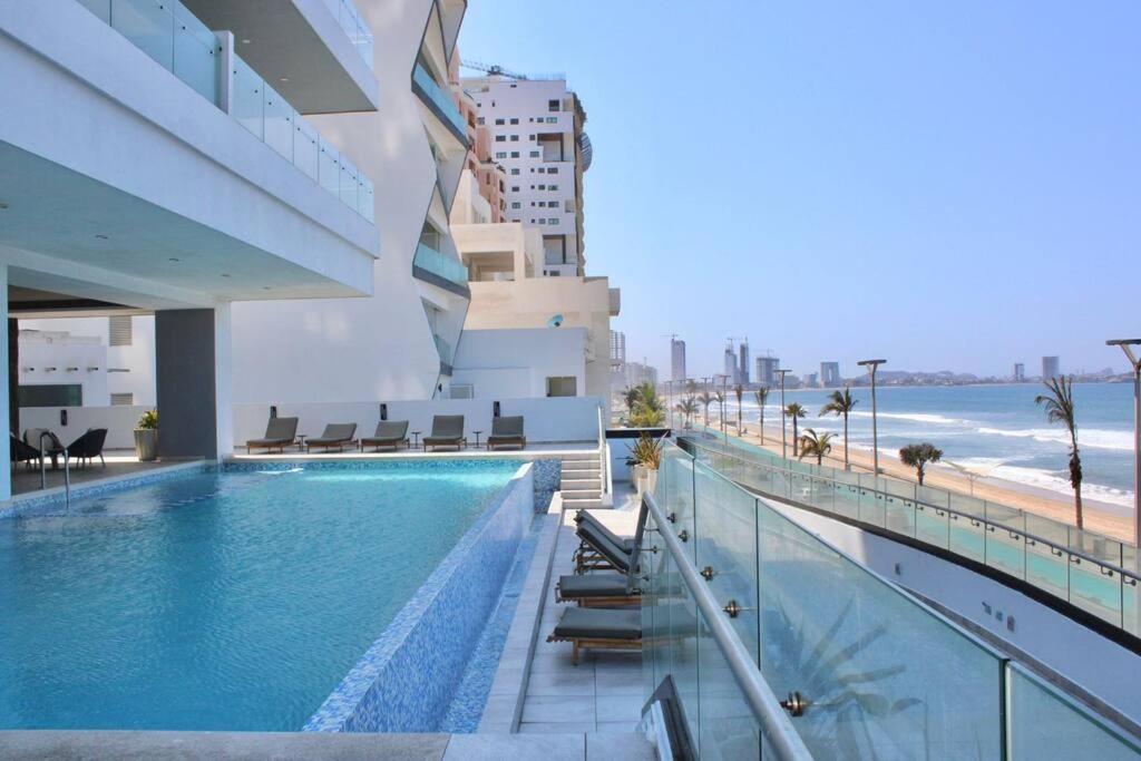 a swimming pool on the side of a building next to the beach at Altomare hermoso depa con vista al mar in Mazatlán