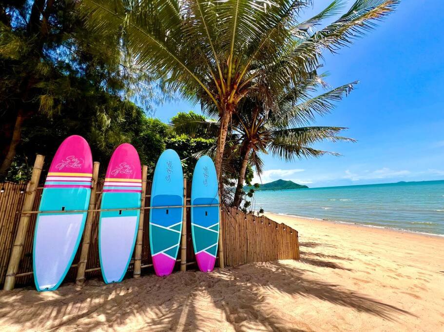 Una fila de tablas de surf apoyadas contra una valla en la playa. en Natural Villas Na Jomtien Pattaya Private Pool, en Bang Sare