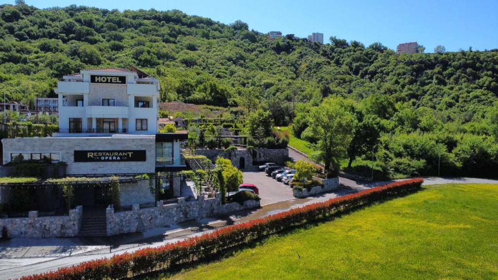 a building in front of a hill with trees at Hotel Opera Jaz in Budva
