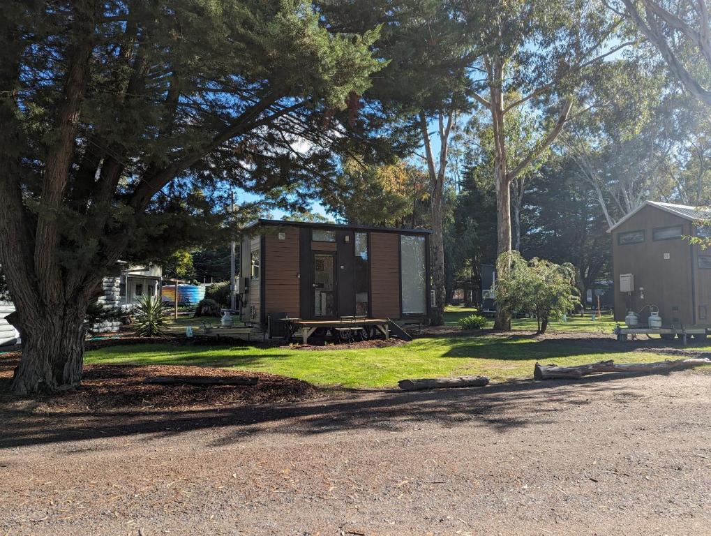 a tiny house sitting on the grass next to a tree at Tiny House 12 at Grampians Edge in Dadswells Bridge