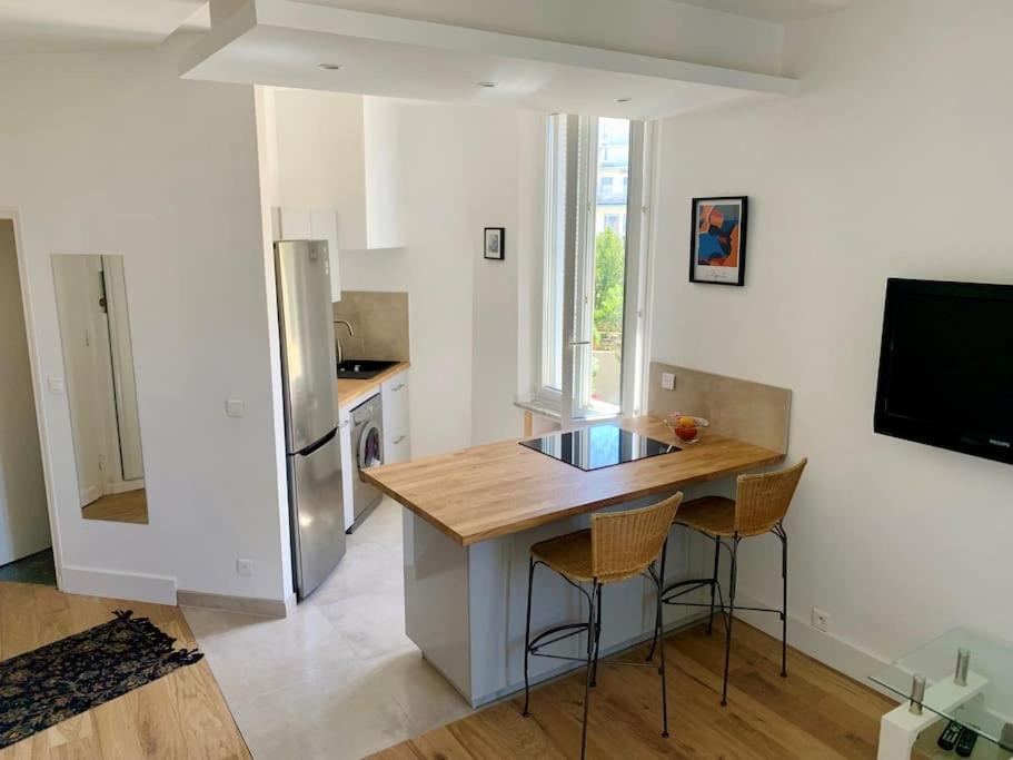 une cuisine avec une table et deux tabourets de bar dans l'établissement Superbe appartement en plein centre de Cannes, à Cannes