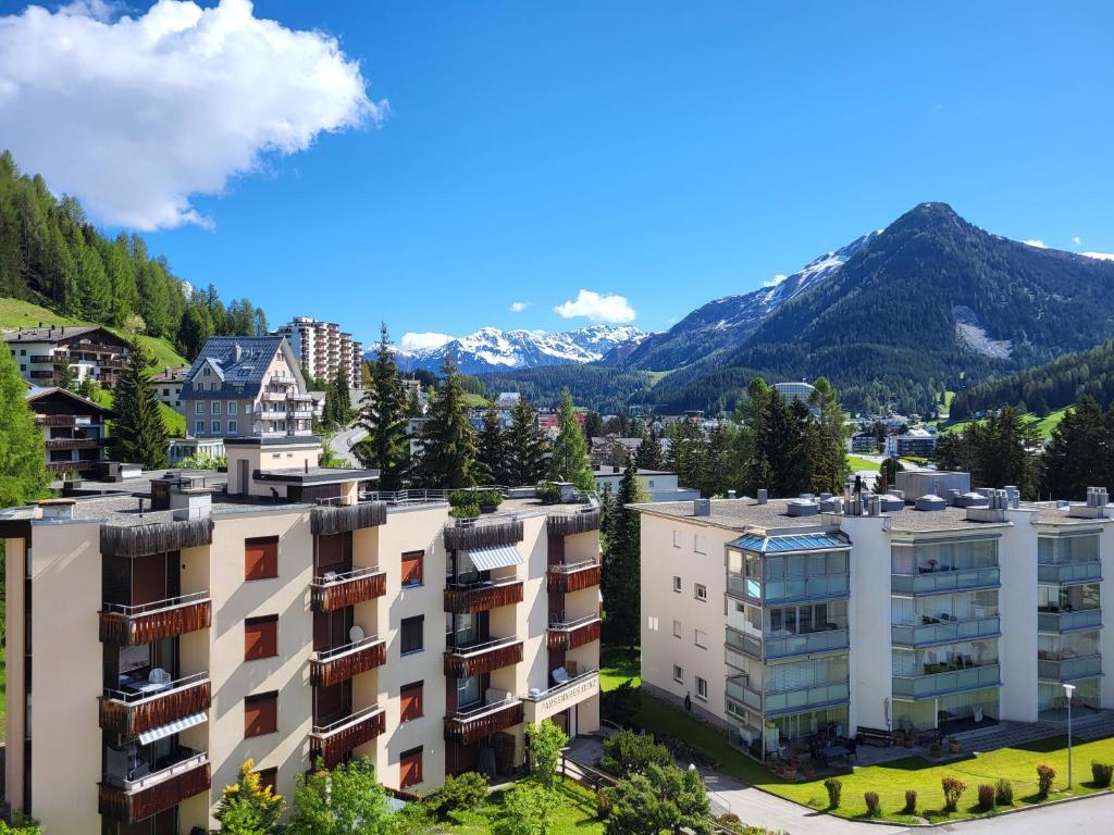 un edificio de apartamentos con montañas en el fondo en Ferienwohnung Parsenn Peaks Panorama en Davos
