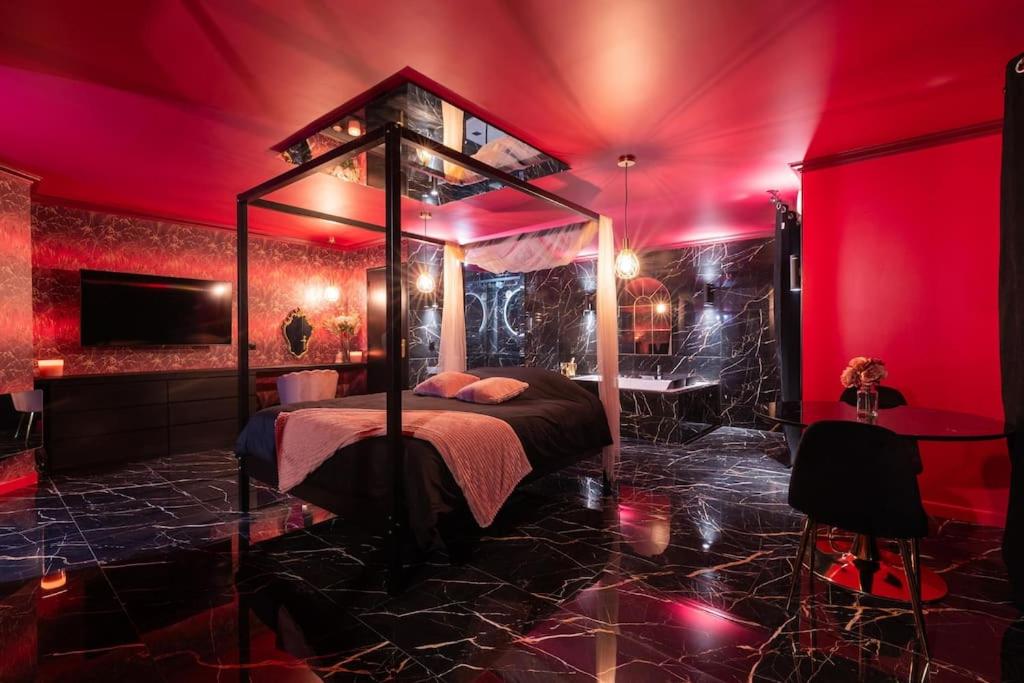 - une chambre rouge avec un lit à baldaquin dans l'établissement L'Evidence, à Magny-le-Hongre