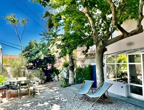 a patio with chairs and a table and a tree at Bord de mer, magnifique appartement de 150m2 avec jardin in Marseille