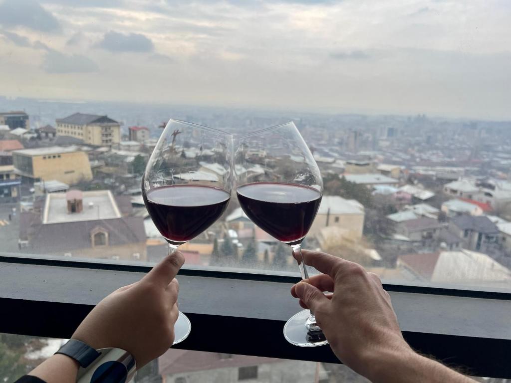 two people holding up wine glasses in front of a window at New Nairi Hotel in Yerevan