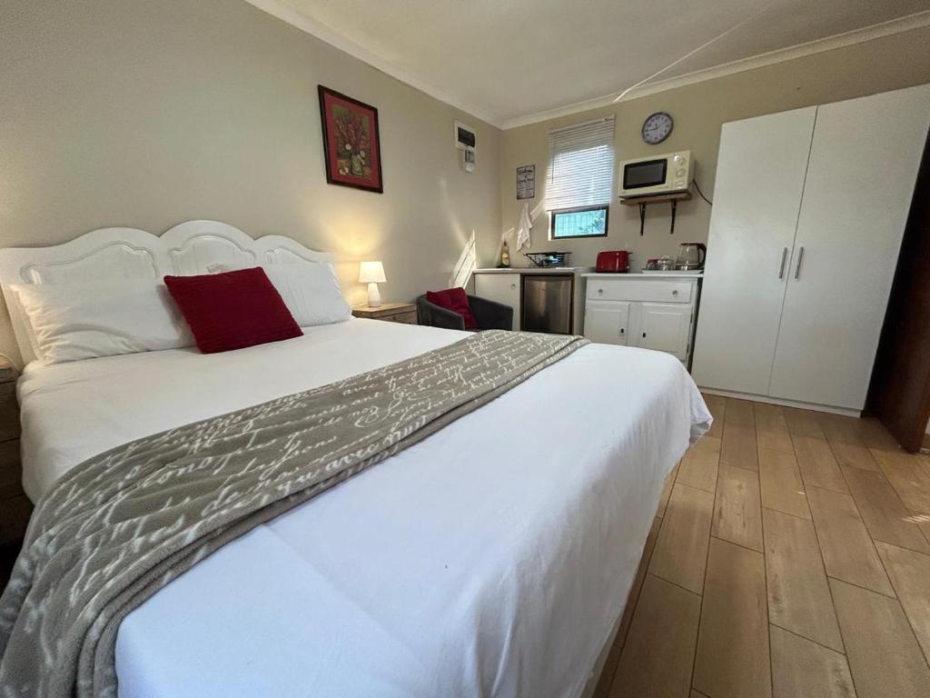 Schlafzimmer mit einem großen weißen Bett und einem roten Kissen in der Unterkunft Khaled Estate Cottages in Hillcrest