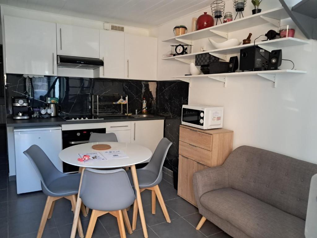 cocina pequeña con mesa, sillas y sofá en Charmante Maison à 15 minutes de la place Comédie en Montpellier