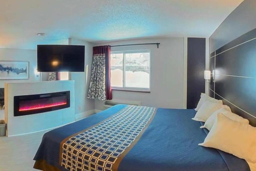 a bedroom with a large bed with a fire place at Coratel Inn & Suites by Jasper Hastings in Hastings