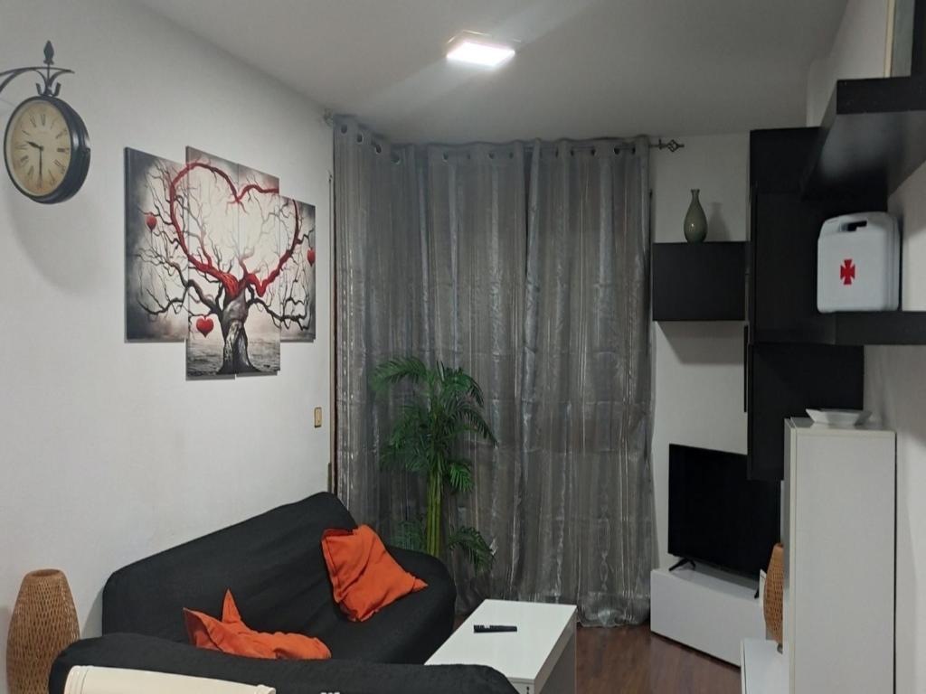 a living room with a black couch and a window at Alojamiento Tierra del Ara in Boltaña