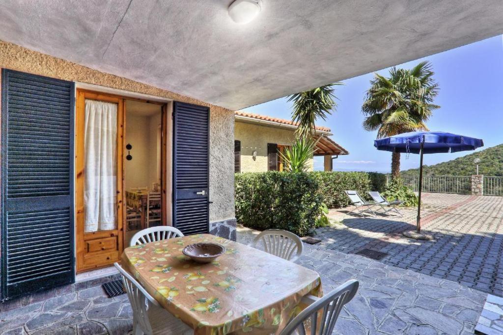 a patio with a table and chairs and an umbrella at Casa Helba - Colle Paradiso Experience in Capoliveri