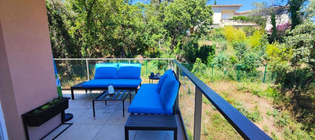 d'un balcon avec des chaises bleues et une vue sur les arbres. dans l'établissement Spacious apartment with lovely terrace, à Saint-Raphaël