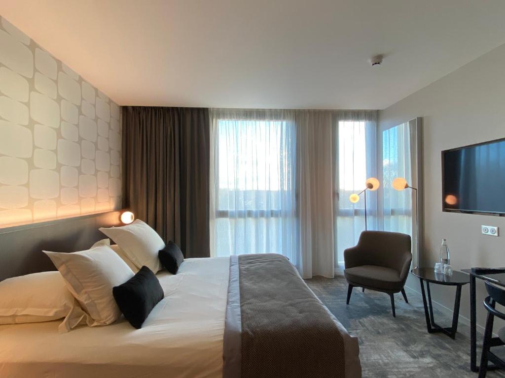 ein Hotelzimmer mit einem großen Bett und einem Stuhl in der Unterkunft Hotel du Pasino in Saint-Amand-les-Eaux