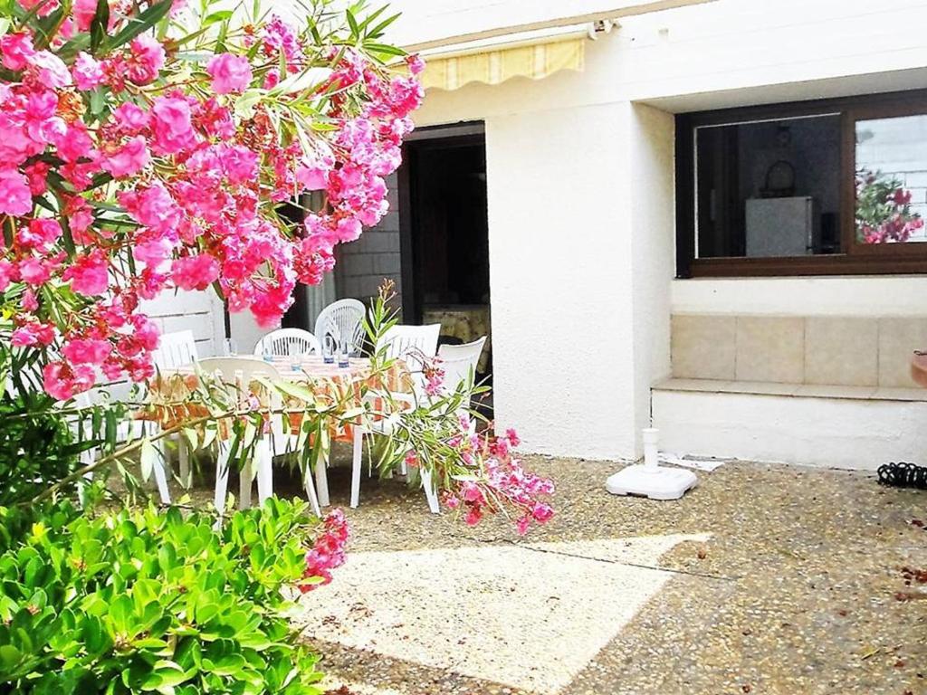une table et des chaises devant une maison ornée de fleurs roses dans l'établissement Villa Duplex 3 Pièces, 7 Couchages, Patio Privatif et Parking à La Grande-Motte - FR-1-790-7, à La Grande Motte