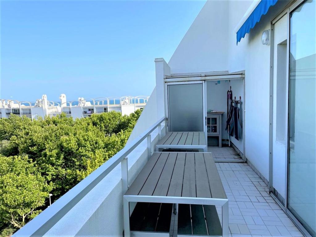 - un balcon dans un bâtiment blanc avec un banc dans l'établissement Appartement proche plage avec terrasse, loggia et parking - FR-1-790-12, à La Grande Motte
