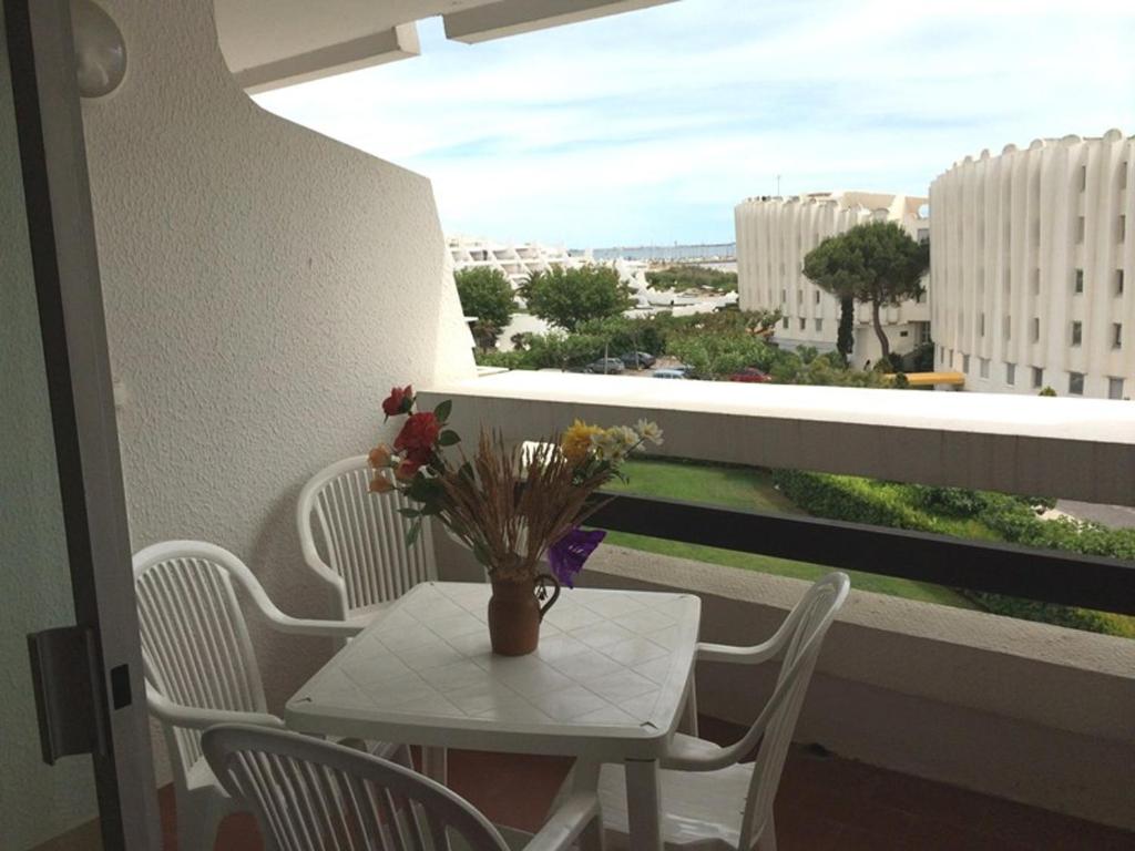 d'une table, de chaises et d'un vase de fleurs sur le balcon. dans l'établissement Studio cabine lumineux 4 pers avec loggia, à 2 pas de la plage et parking privé - La Grande Motte - FR-1-790-10, à La Grande Motte