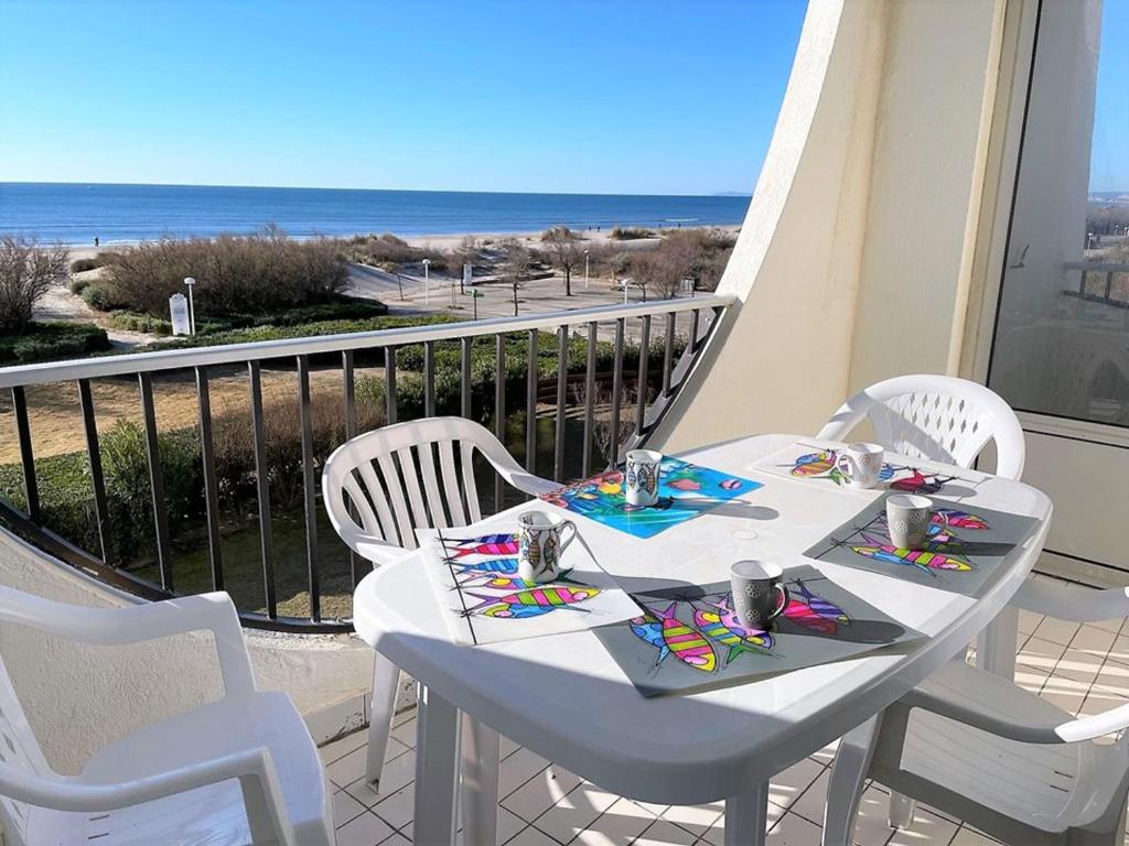 une table blanche et des chaises sur un balcon avec l'océan dans l'établissement Appartement 1 chambre en bord de mer, 34m² d’extérieurs, parking privé, La Grande Motte - FR-1-790-22, à La Grande Motte